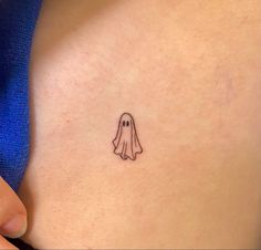 a small ghost tattoo on the back of a woman's stomach is seen in this image