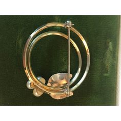 This lovely 1950s Krementz Pearl and Leaf Double Circle Brooch is a traditional piece of vintage jewelry that will soon become your go-to. The lovely design of this pin / brooch incorporate a trio of freshwater pearls with two leaves and a double circle creates an eye catching yet calm, zen feel. This brooch would look stunning on any scarf or lapel, and it will be in style for years to come. Original Box included.  Dimension: approximately 2"W x 2"L Condition: Excellent vintage condition; pleas Vintage White Gold Round Brooches, 1930s Brooch, Luxury Mid-century Evening Brooches, Vintage Gold Brooch With Pearl Pendant, Vintage Pearl Gold Brooches, Gold Brooches, Georg Jensen, Pearl Brooch, Rhinestone Brooches