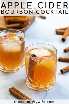 two glasses of apple cider bourbon cocktail on a marble table with cinnamon sticks and apples