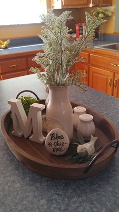 a wooden tray with flowers in it on top of a kitchen counter next to the letter m