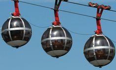 two gondolas hanging from wires against a blue sky