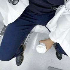 a man in a white coat and blue pants with his feet up on the floor