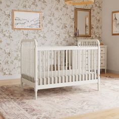 a white crib sitting on top of a wooden floor next to a dresser and mirror