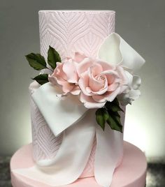 a pink and white wedding cake with flowers on top