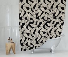 a black and white shower curtain with leaves on it in front of a bathtub