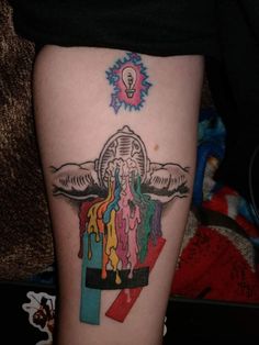 a person with a tattoo on their leg that has some colors coming out of it