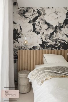 a bedroom with floral wallpaper and white bedding