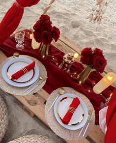 the table is set with red and white plates, napkins, silverware and candles