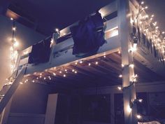 a loft bed with lights and clothes hanging from it