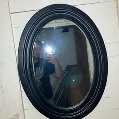 a man taking a selfie with his cell phone in front of a round mirror