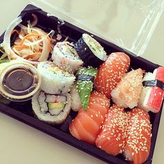 a tray with sushi and sauce on it