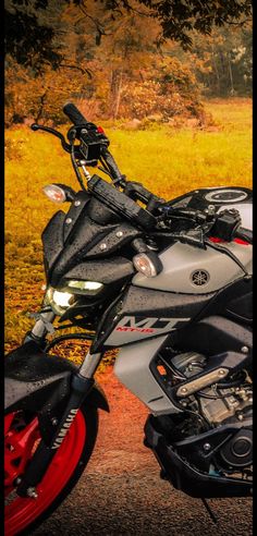 a motorcycle parked on the side of a road in front of some grass and trees