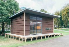 a small brown building sitting on top of a lush green park covered in trees and grass