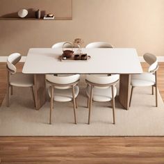 a dining room table with white chairs and a beige rug in front of the table