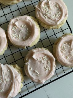 frosted cookies on a cooling rack with white sprinkles and pink icing