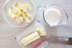 there are some pieces of cheese on the table next to a measuring cup and knife