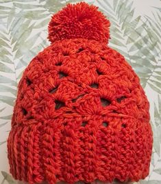 a red crocheted hat sitting on top of a table