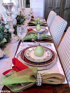 a dining room table set for christmas with place settings and napkins on the plates