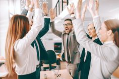 a group of business people raising their hands in the air with one man wearing a suit and tie