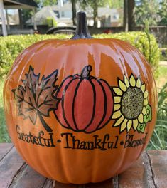 an orange pumpkin with the words grateful, thanks and sunflowers painted on it