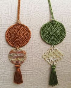 two necklaces with beads and tassels hanging on a white wall next to each other