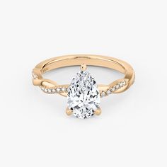 a yellow gold engagement ring with a pear shaped diamond in the center and side stones