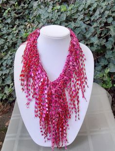 "Hand knit Ribbon Scarf/Necklace This ribbon scarf/necklace is a shaggy character, but delicate and lightweight. The scarf is 60\" long, including the fringe and 2\"wide. The yarn is a fine Italian trellis yarn, a type of ribbon yarn. This is a pink scarf with a combination of pink and red fringe, with a hint of sparkle. Perfect for the Holiday's It is pictured tied in a classic knot. Each of the many pieces of fringe is hand crocheted to the ends of the scarf and around the sides.   Great for t Shaggy Character, Ribbon Yarn Scarf, Ribbon Scarf, Statement Scarf, Red Fringe, Decatur Ga, Scarf Yarn, Scarf Necklace, Pink Scarf