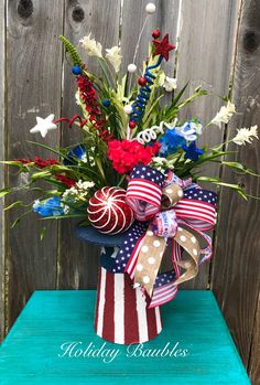 a patriotic arrangement in a vase on a blue table with wooden fence and wood planks