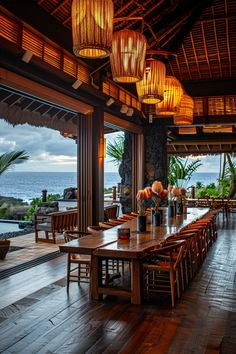 an outdoor dining area with large wooden tables and chairs, overlooking the ocean on a cloudy day