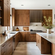 a kitchen with wooden cabinets and white counter tops, along with a vase filled with flowers