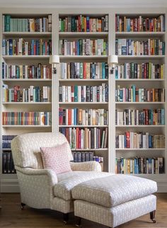 a white chair sitting in front of a bookshelf filled with lots of books