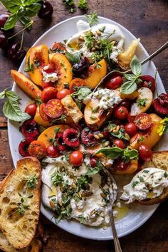 a white plate topped with bread and lots of veggies next to some cherry tomatoes