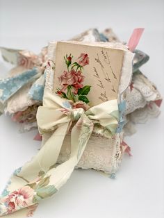 an old book with flowers on it and ribbon tied around the cover is sitting on a table