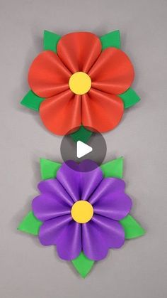 three different colored flowers on a gray surface with one red and one purple flower in the center