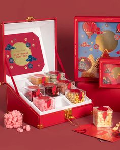 an open red box filled with sweets and candies on top of a table next to other boxes