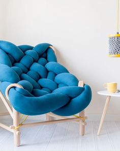 a blue chair sitting on top of a white floor next to a table and lamp