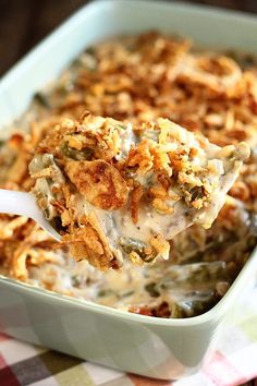 a spoon full of food in a casserole dish on a checkered table cloth