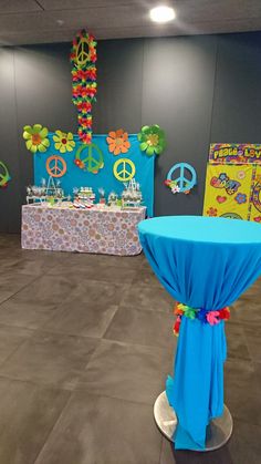 a table with blue cloth on it in front of a wall decorated with peace signs