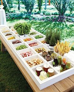 a picnic table with food and drinks on it in front of a grassy lawn area