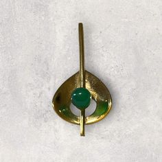 a close up of a metal object on a white surface with a green ball in the center