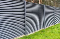 a black metal fence with green grass and trees in the background