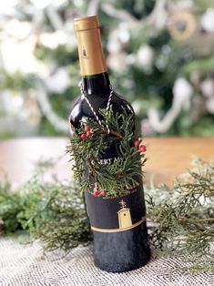 a bottle of wine sitting on top of a table covered in greenery and berries