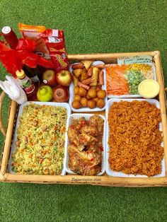 a tray filled with lots of food on top of a grass covered floor next to drinks