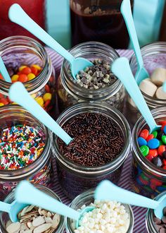 several jars filled with different types of candy and candies in them, including spoons