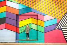 a woman standing in front of a colorful wall