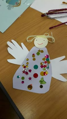 a paper angel sitting on top of a wooden table next to beads and other items