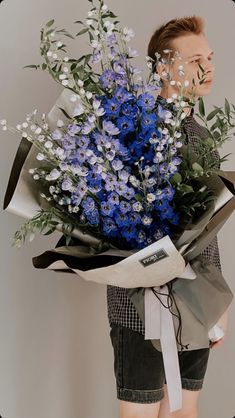 a woman holding a bouquet of blue flowers