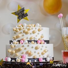 a three tiered cake with pink and white decorations on it, surrounded by confetti