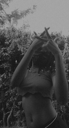 black and white photograph of a woman holding her hands up to her face with trees in the background