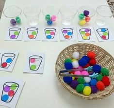 a table topped with lots of different colored pom poms next to cups and spoons